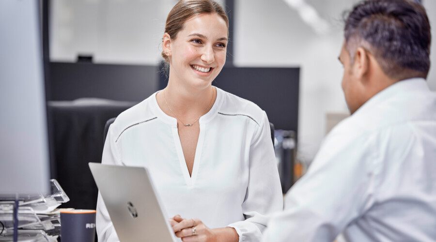 Woman smiling at a man sitting in front of a laptop